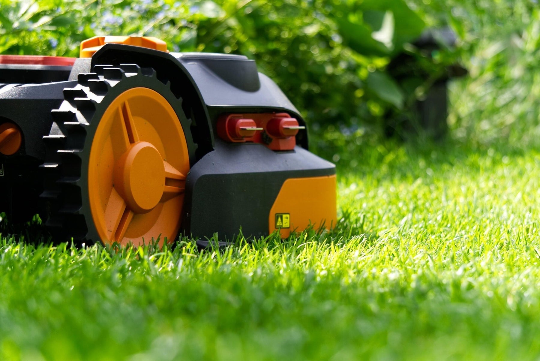 Domestic robot lawnmowe side on , in close up pictured against a luscious green lawn