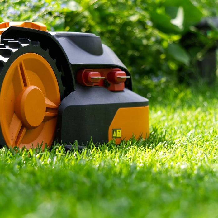 Domestic robot lawnmowe side on , in close up pictured against a luscious green lawn