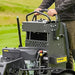 Person holding a lawn mower with a blurred grassy background