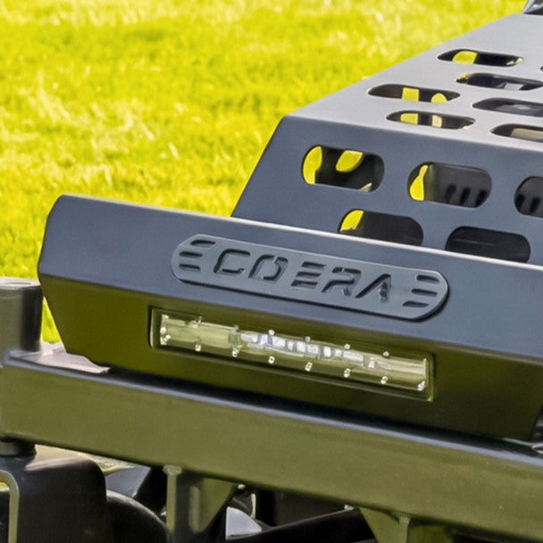 Close-up of a vehicle bumper with 'Cobra' branding on a grassy background