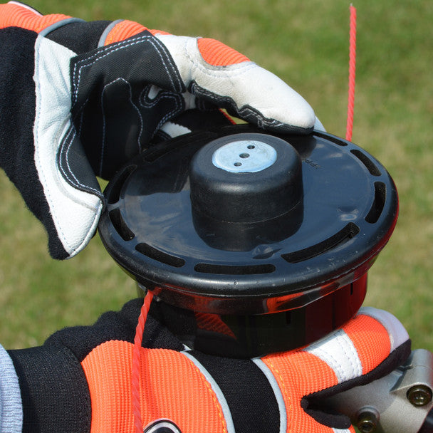 Person wearing orange and black gloves holding a Cobra BC330CU blade against a grassy background