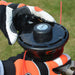 Person wearing orange and black gloves holding a Cobra BC330CU blade against a grassy background