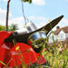 Cobra BC330CU grass strimmer large blade in grass, blurred house and trees in the background