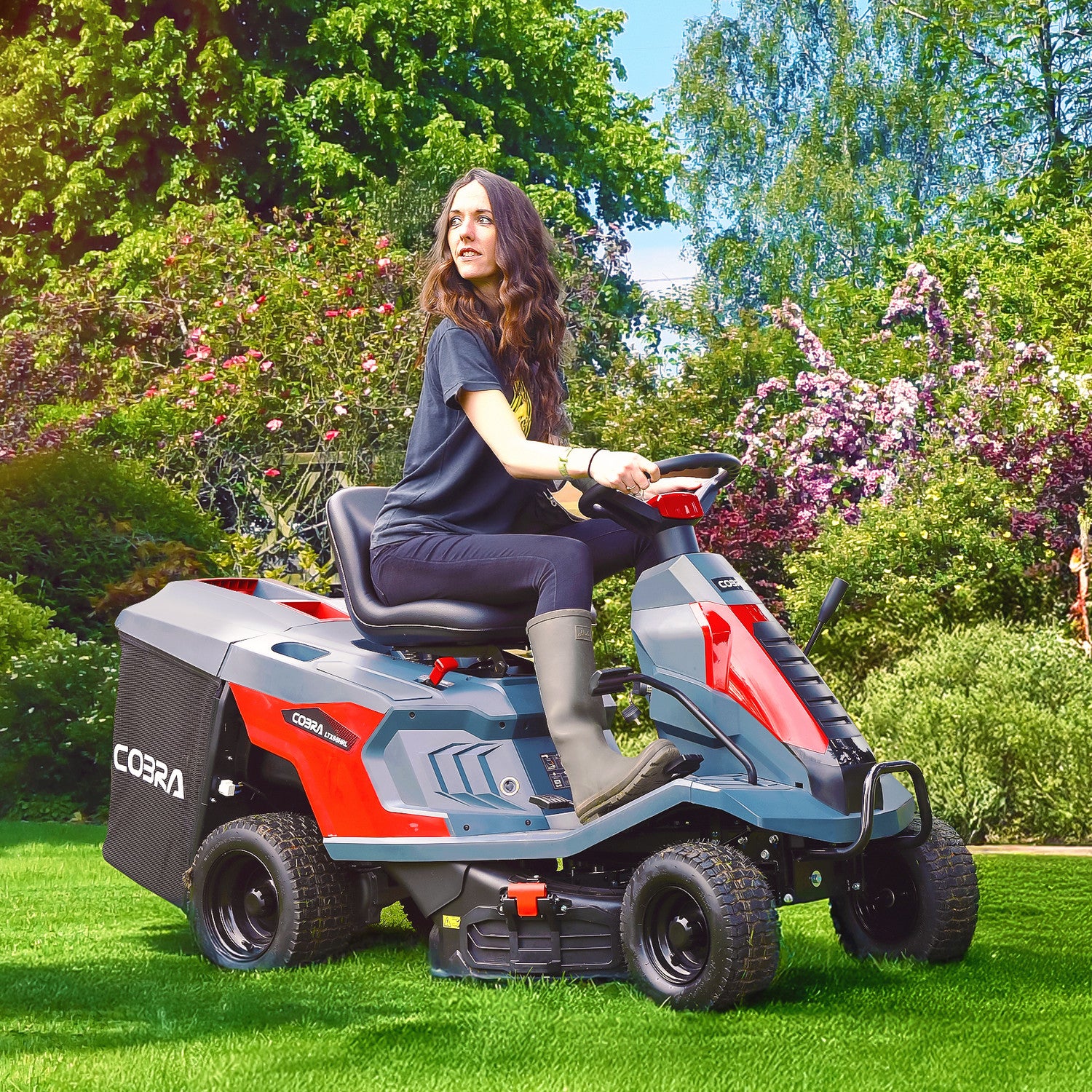 Person operating a Cobra LTX66HRL riding lawn mower in a garden setting