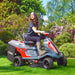 Person operating a Cobra LTX66HRL riding lawn mower in a garden setting