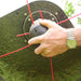 Person using a string trimmer on grass with red strings on a Cobra WT56B Wheeled trimmer