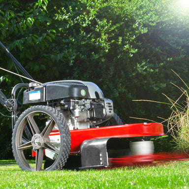 Cobra WT56B Wheeled trimmer, in use on grass with trees in the background.