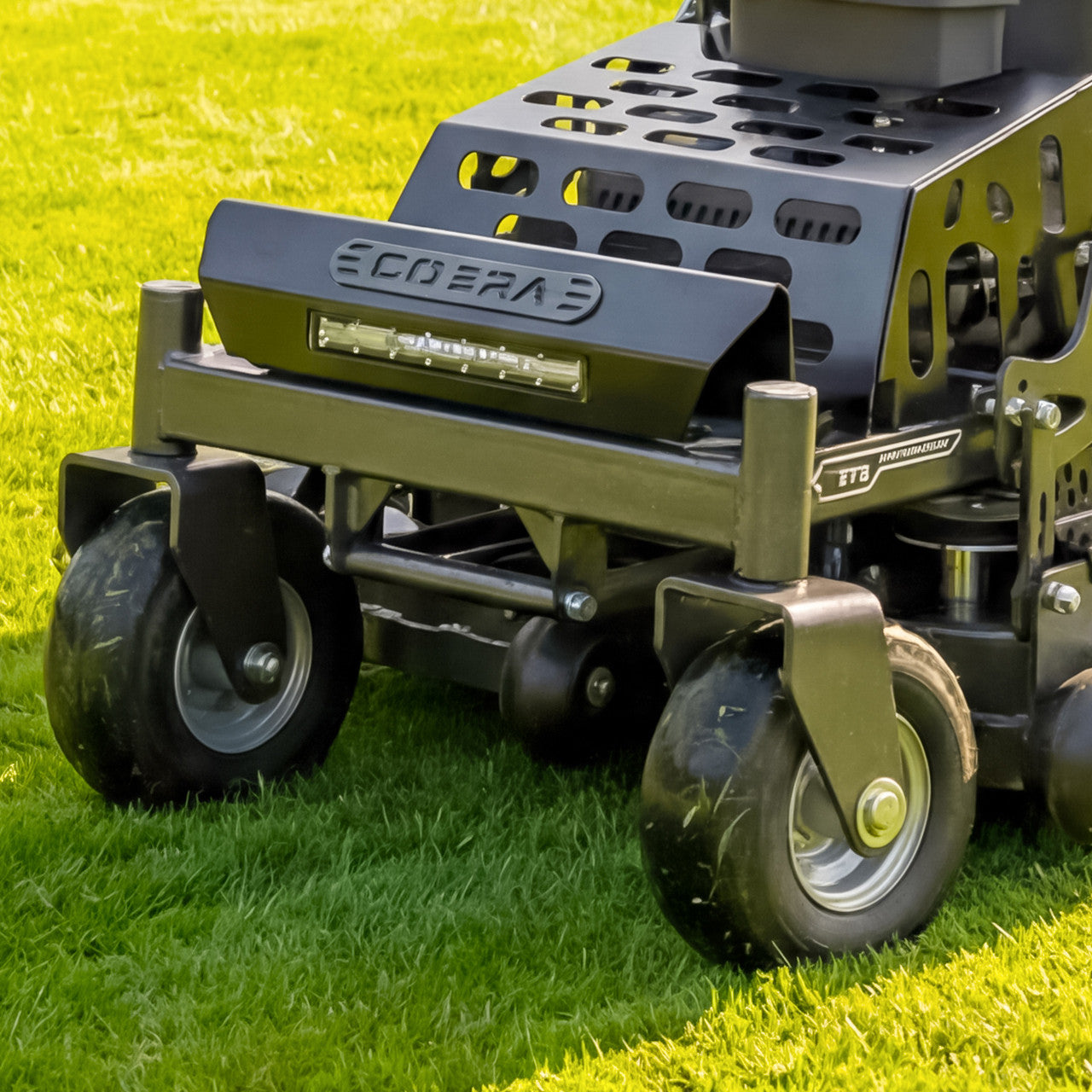 Close-up of a cobra 36" stand on lawn mower with 'cobra' branding on a grassy background