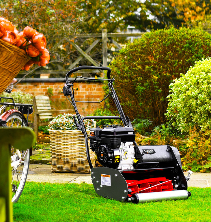 Wide shot image of a Cobra Fortis 17b on a finely cut lawn with bushes in the background