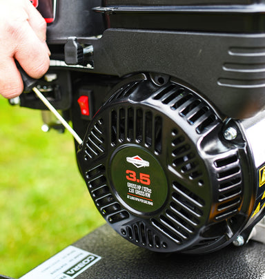 Close-up of a  briggs and straton being started via the pull cord starter. All against a grassy background.