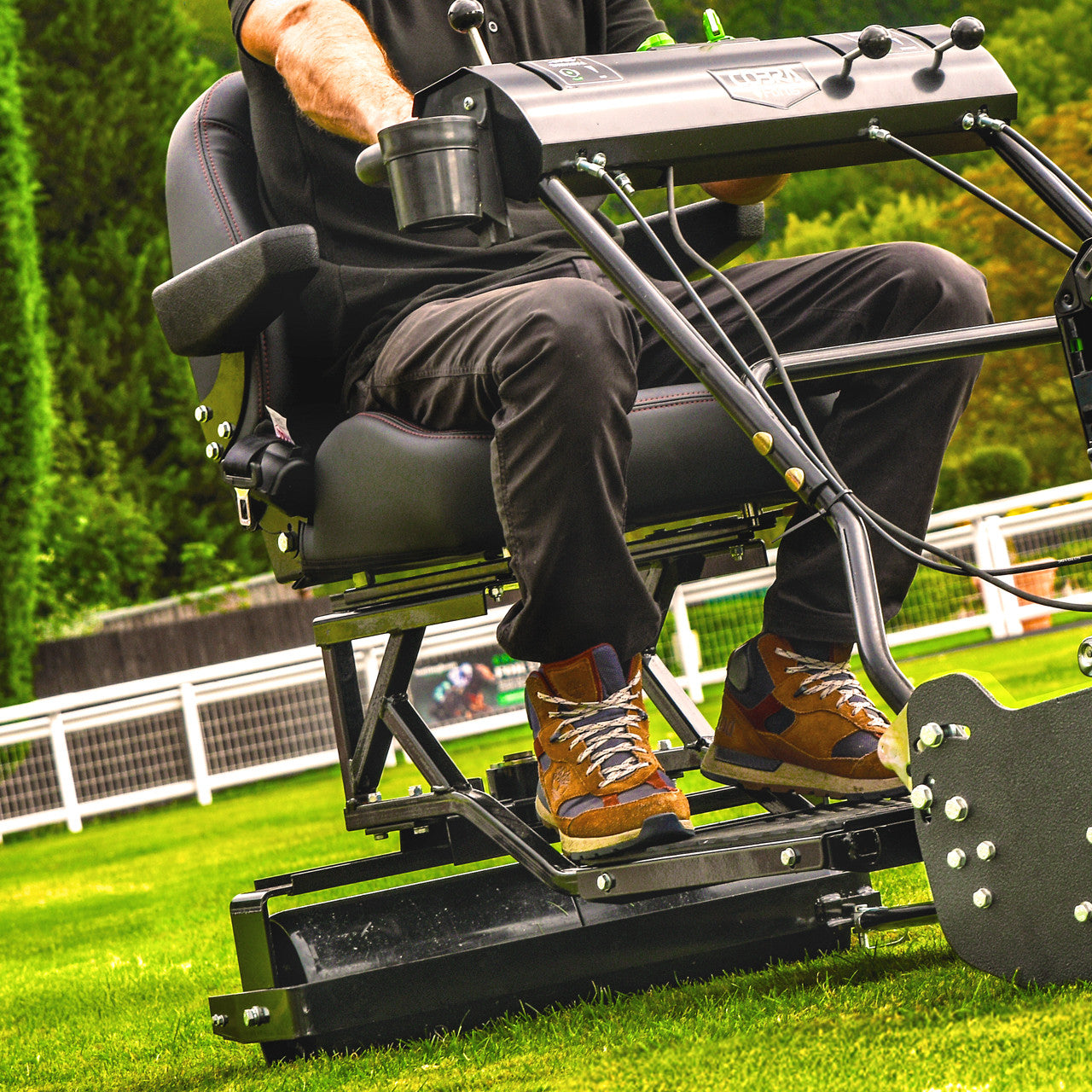  Cobra fortis 34'. Person using a trailed seat attachment on a grassy area.