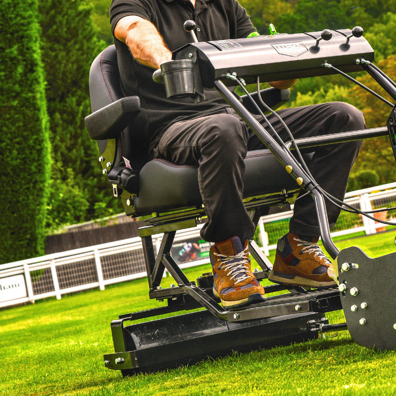 Image of Cobra Fortis 34' Stadium trailed seat. Lifestyleimage shows man riding seat on grass.