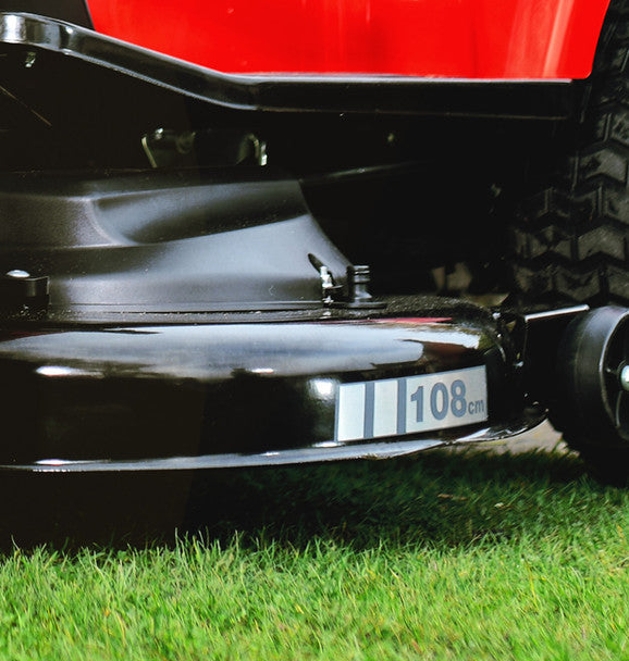 Close-up of a cobra ride on lawn tractorcutting deck on grass.