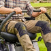 Person operating a a cobra zero turn lawn mower on a grassy area with a stone wall in the background.