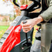 Person operating the blade engagementon a  obra LTX66HRLred and black ride on lawn mower with a blurred outdoor background