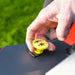 Hand pressing a yellow blade engagement button on a Cobra premium ride on lawn tractor with a green background
