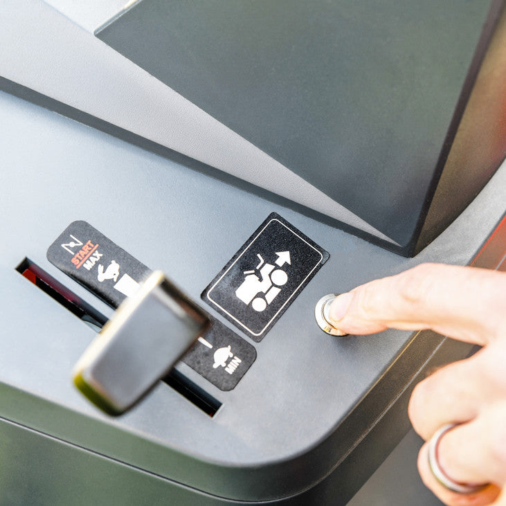 Close up of a finger pointing at the reverse cut button on a Cobra premium ride on lawn mower.