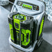 Green and black power tool battery being charged on a charger with a digital display.