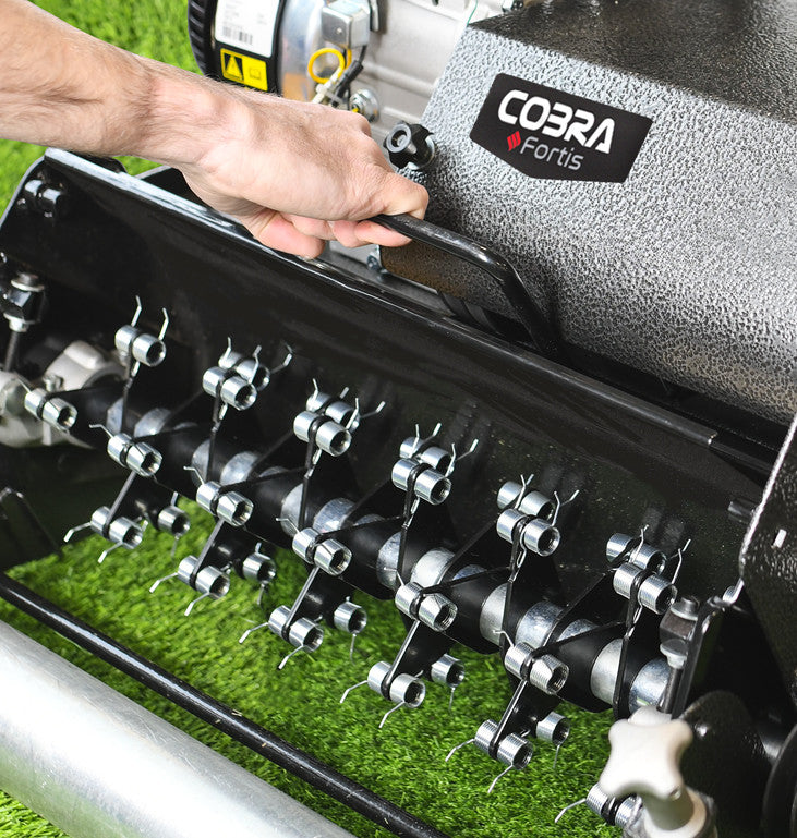 Close-up image of a  hand removing a Cobra Fortis lawn aeration tool on grass