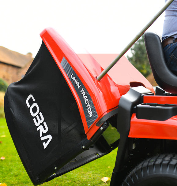 Red Cobra lawn tractor on a grassy area with a blurred background